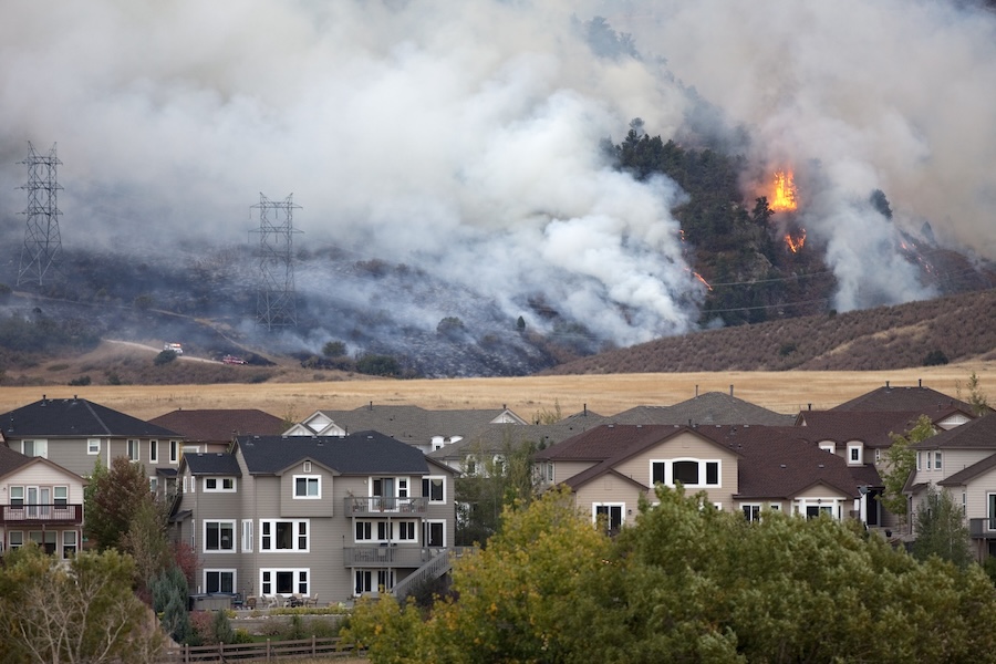 Pine trees and scrub oak burn behind homes due to wildfires in the hills 